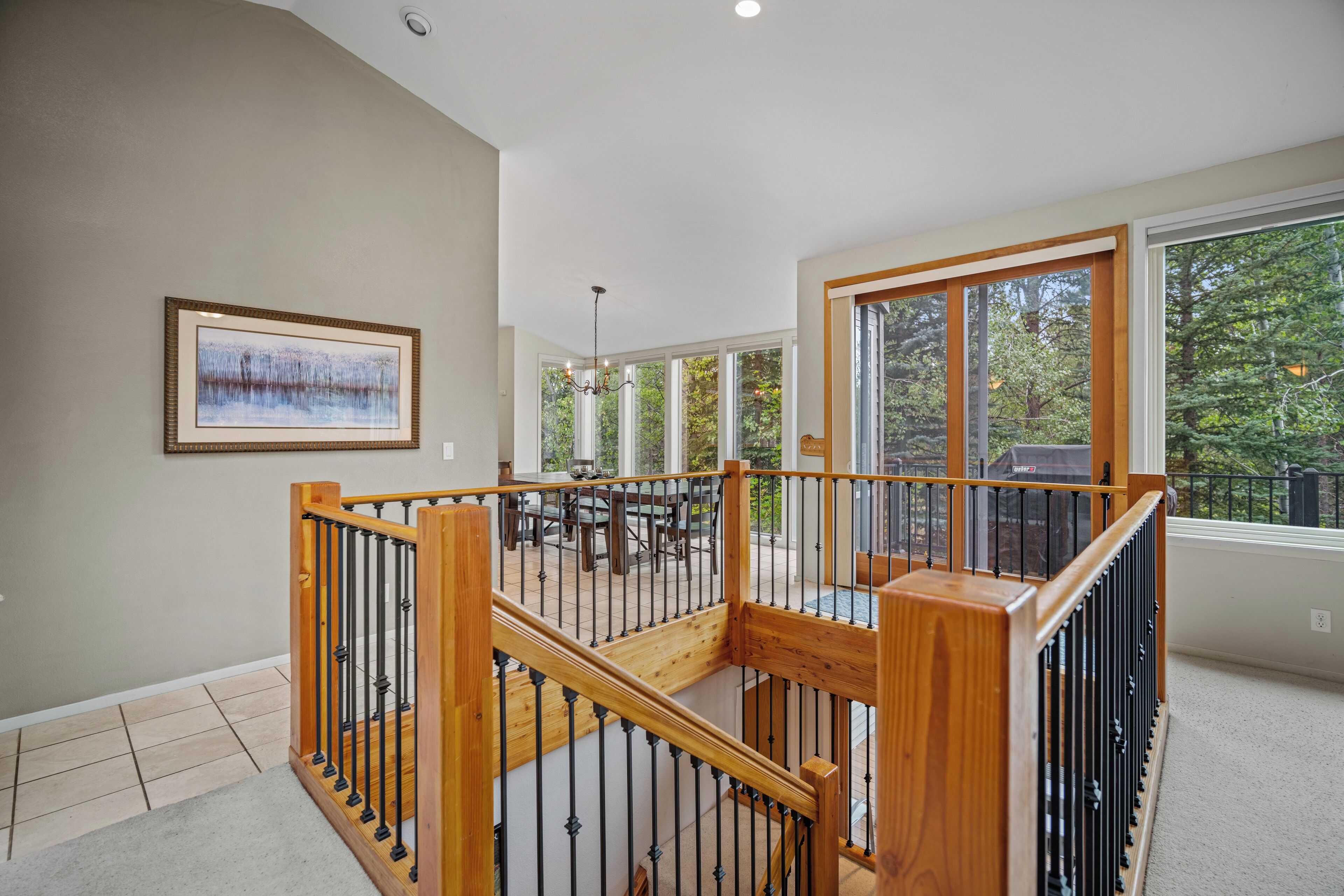 A spacious indoor area with a wooden staircase, large windows, and a view of the outdoors.