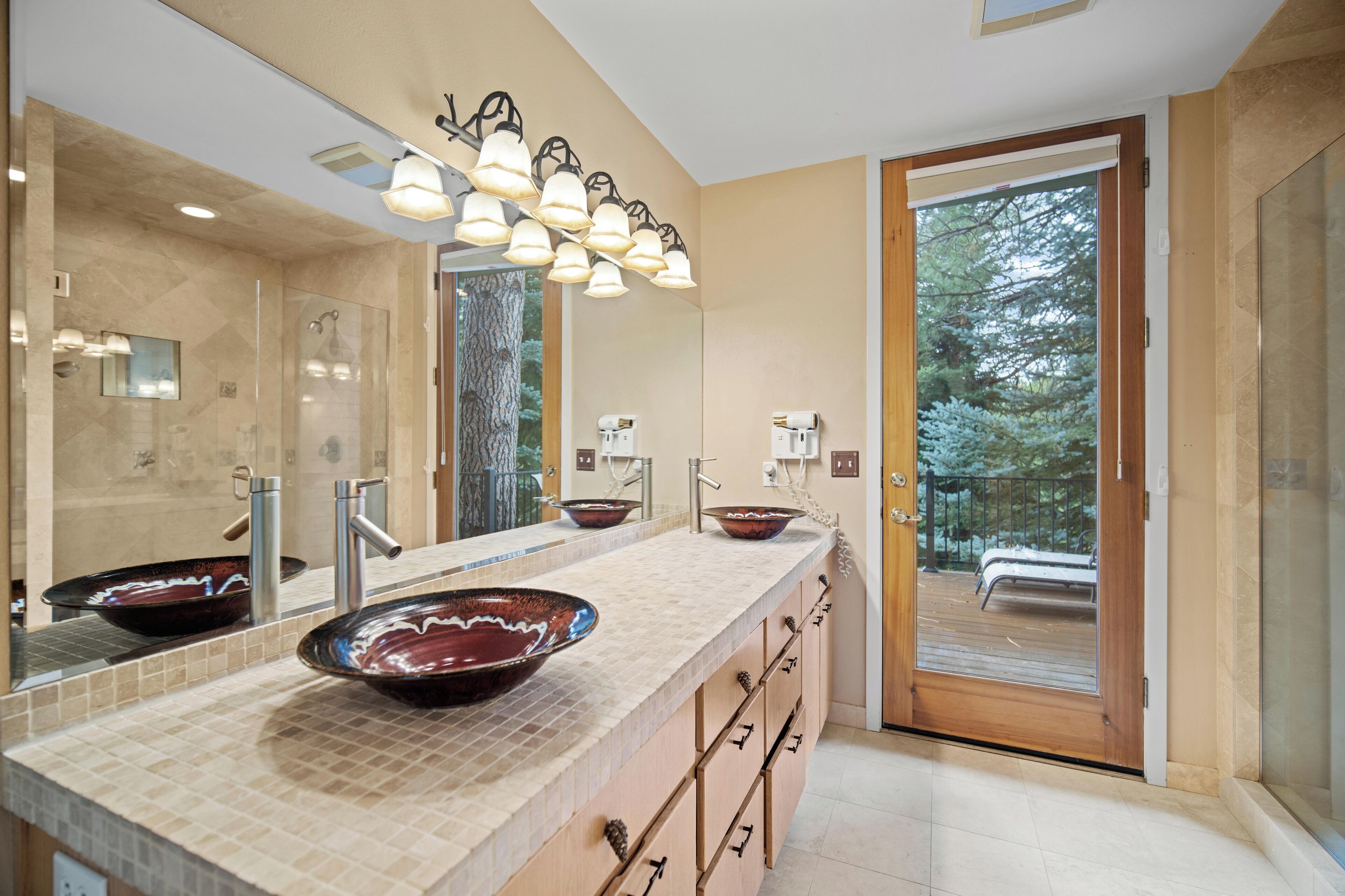 A modern bathroom with a large mirror, two sinks, and a shower area.