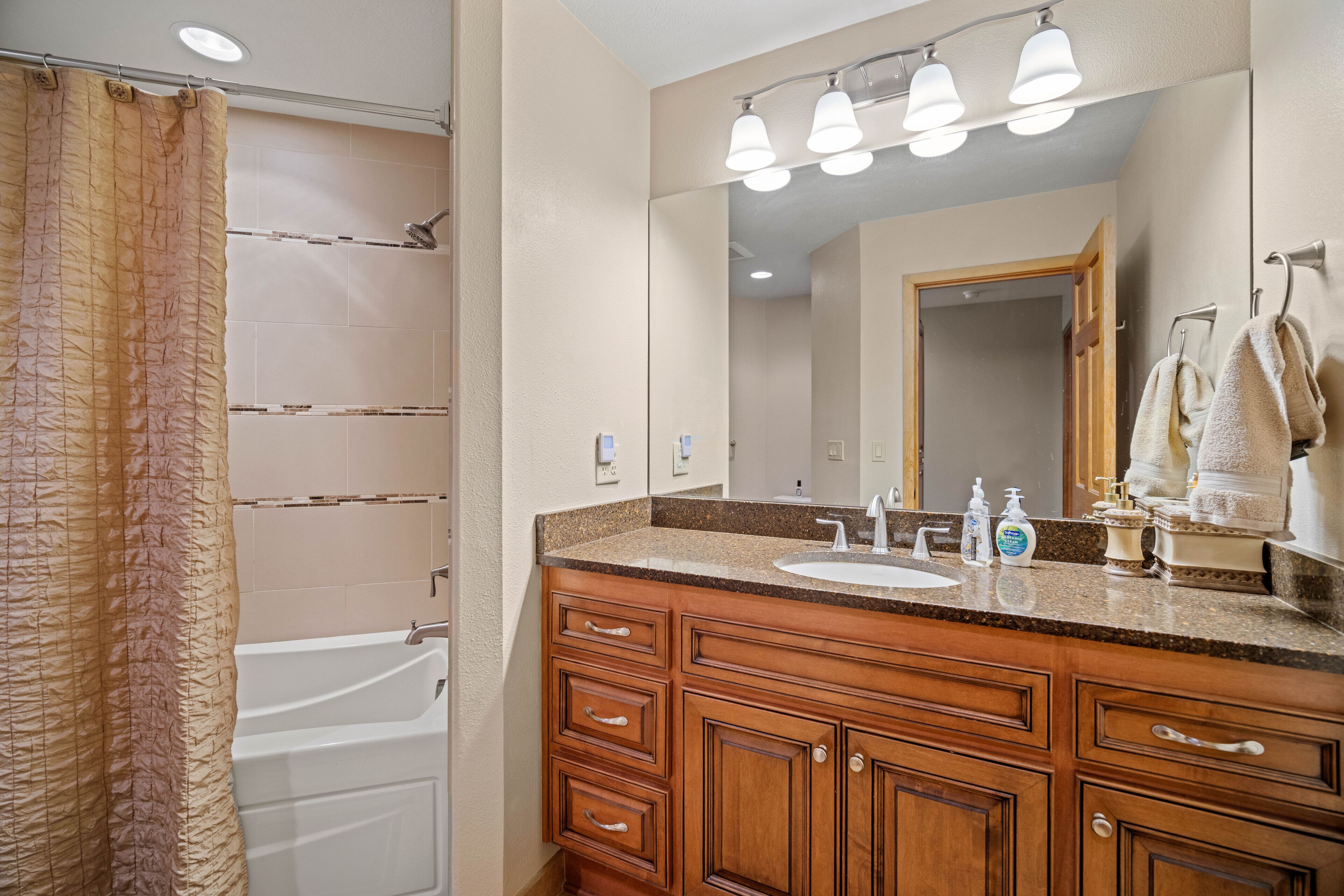 A bathroom with a bathtub, a sink, and a vanity with drawers.