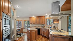 A modern kitchen with wooden cabinets, stainless steel appliances, and a granite countertop. - Sunriver Retreat with Access to The Cove (Sunriver)