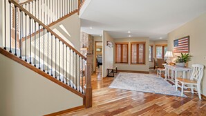 A spacious living area with a wooden staircase, a large rug, and a dining table with chairs. - Sunriver Retreat with Access to The Cove (Sunriver)