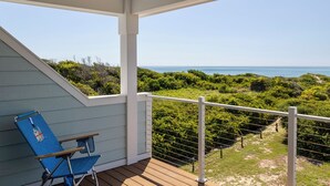 A covered outdoor area with a view of the ocean, a blue chair, and a wooden deck. - Judi's Place, Oceanfront House in Salter Path, NC! (Salter Path)