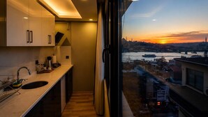 A narrow kitchen with a view of a sunset over a cityscape. - ART Karakoy Hotel (Istanbul)
