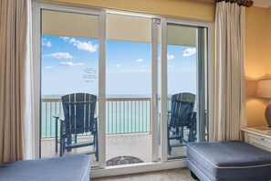 Une pièce dotée d’une porte-fenêtre coulissante donnant sur un balcon avec des chaises et une vue sur l’océan.