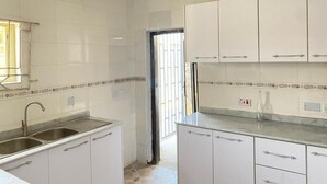 A kitchen with white cabinets, a stainless steel sink, and a tiled backsplash. - Inviting 8 Bed House in Lekki (Lekki)