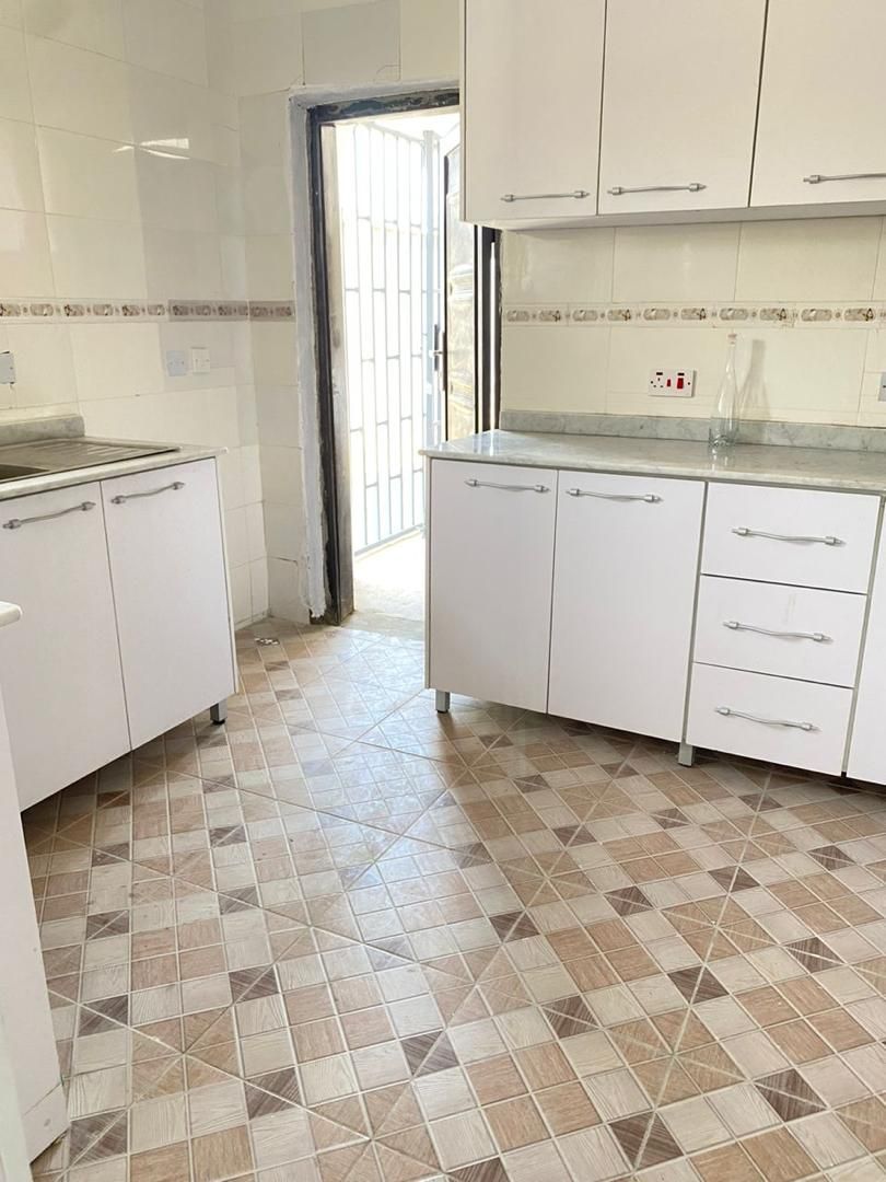 A kitchen with white cabinets, a tiled floor, and a countertop.