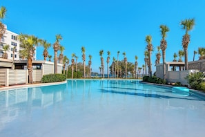 Una piscina con palmeras y edificios modernos al fondo.