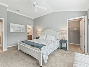 A bedroom with a bed, bedside tables, a ceiling fan, and a walk-in closet. - Stay in Style near the Golf Course in the Village of Fenney! (The Villages)