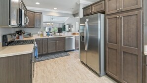 Une cuisine moderne avec des meubles en bois foncé, des appareils électroménagers en acier inoxydable et un îlot central.