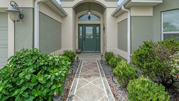 A house with a green door, a covered entrance, and a tiled pathway leading to the door. - 3/2 Designer with a Golf Cart, close to Lake Sumter & Brownwood!!! (The Villages)