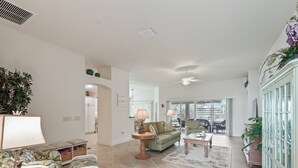 A spacious living room with a sofa, armchairs, a coffee table, and a dining area. - 3/2 Designer with a Golf Cart, close to Lake Sumter & Brownwood!!! (The Villages)