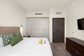 Una habitación de hotel con una cama, una mesita de noche, un armario, un televisor y un aparador.
