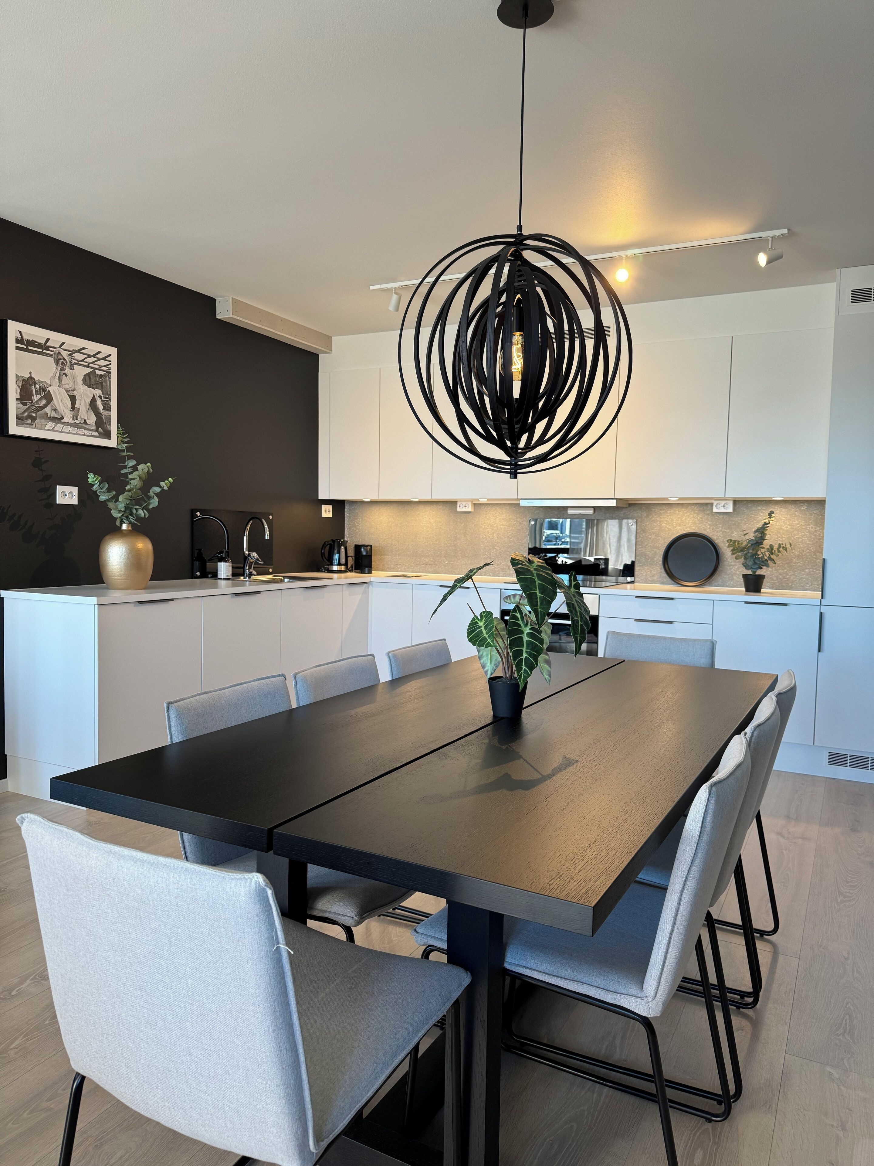 A modern kitchen with a central island, white cabinets, and a pendant light.
