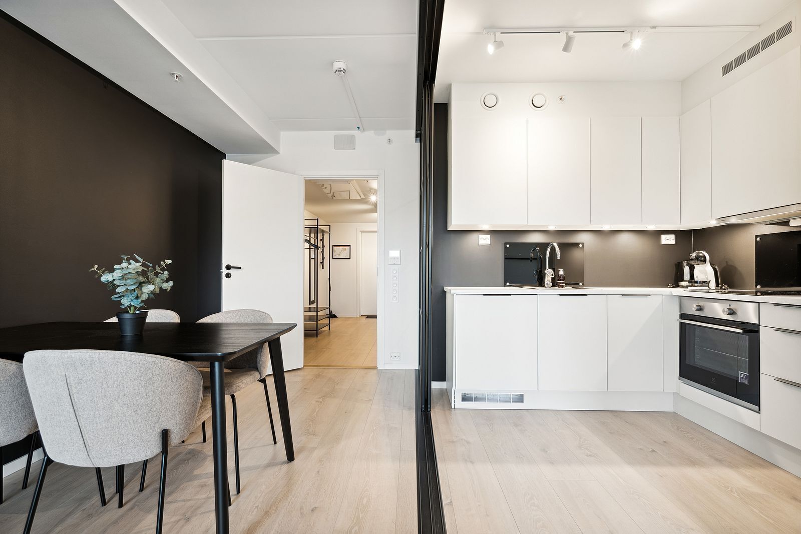 A modern kitchen with white cabinets, a central island, and a dining area with a table and chairs.