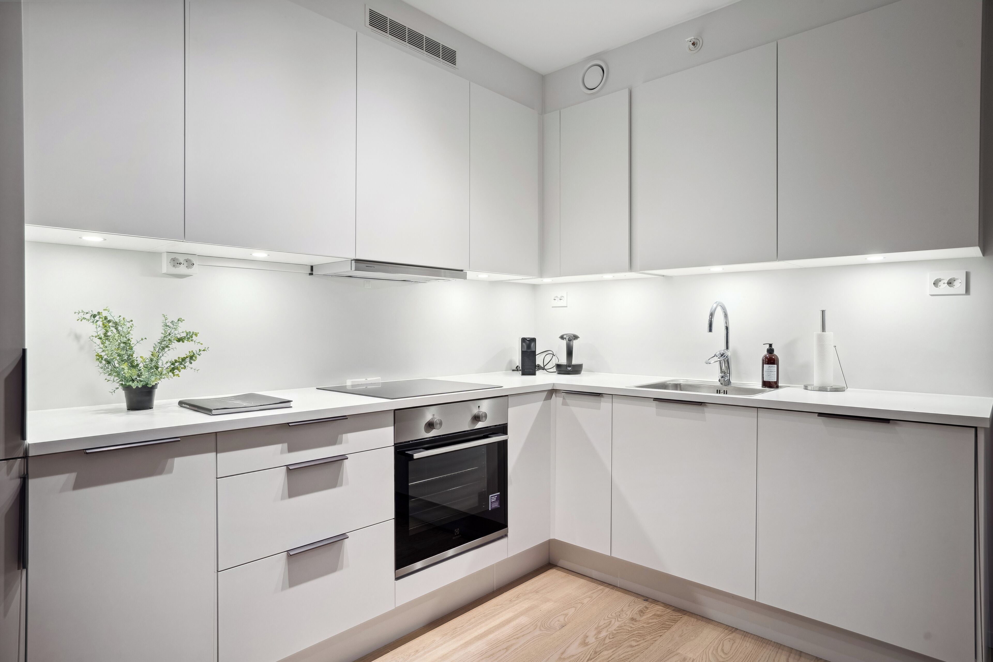 Una cocina moderna con armarios blancos, un horno negro y un lavamanos con grifo.