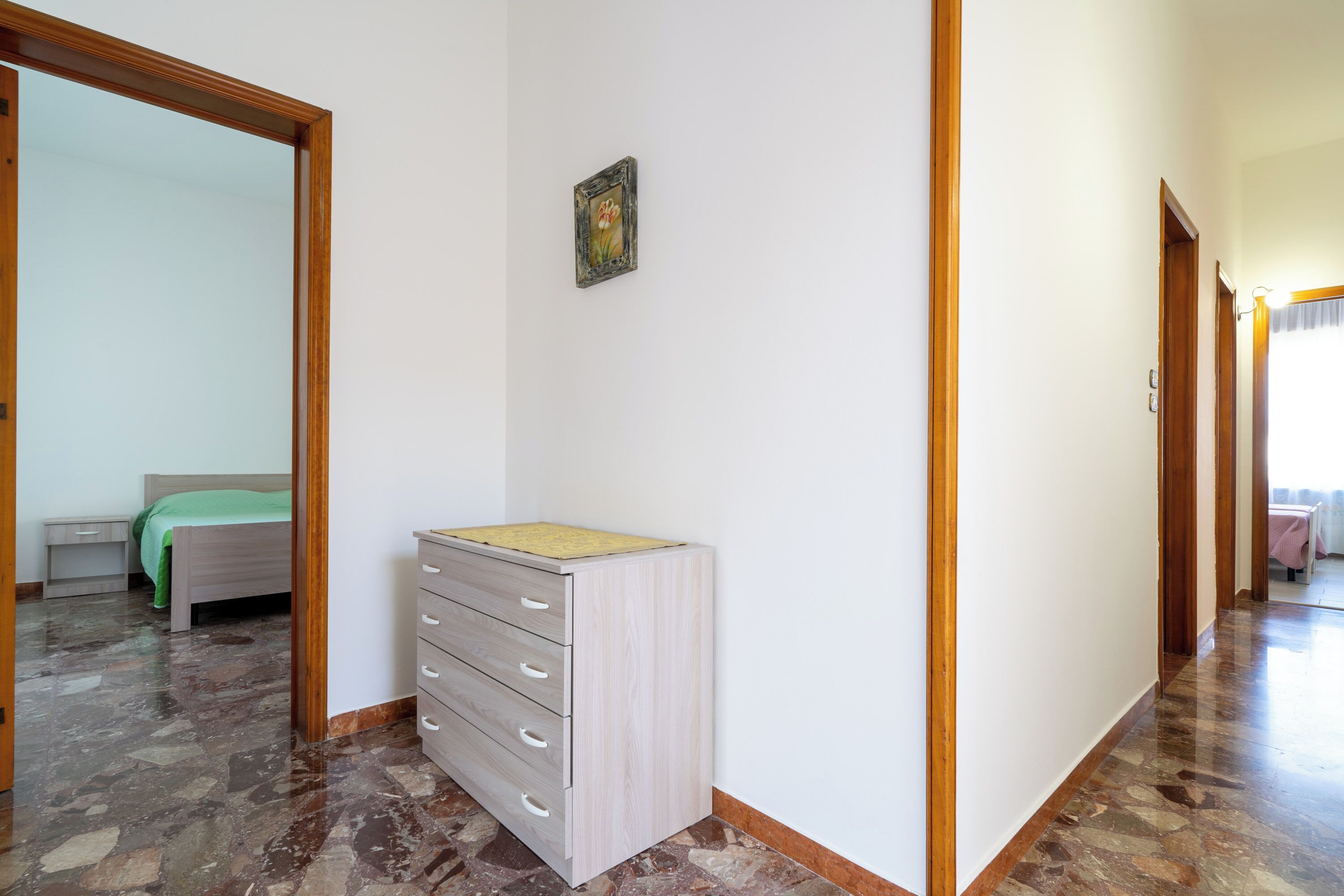Um corredor com uma cama, um penteado e um quadro na parede.