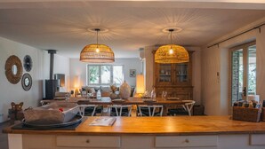 A spacious kitchen with a large island, pendant lights, and a built-in stove. - Maison La Hulotte (Lussan)