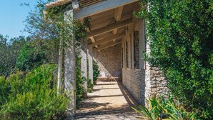 A covered outdoor area with stone walls and a gravel path leading to a seating area. - Maison La Hulotte (Lussan)
