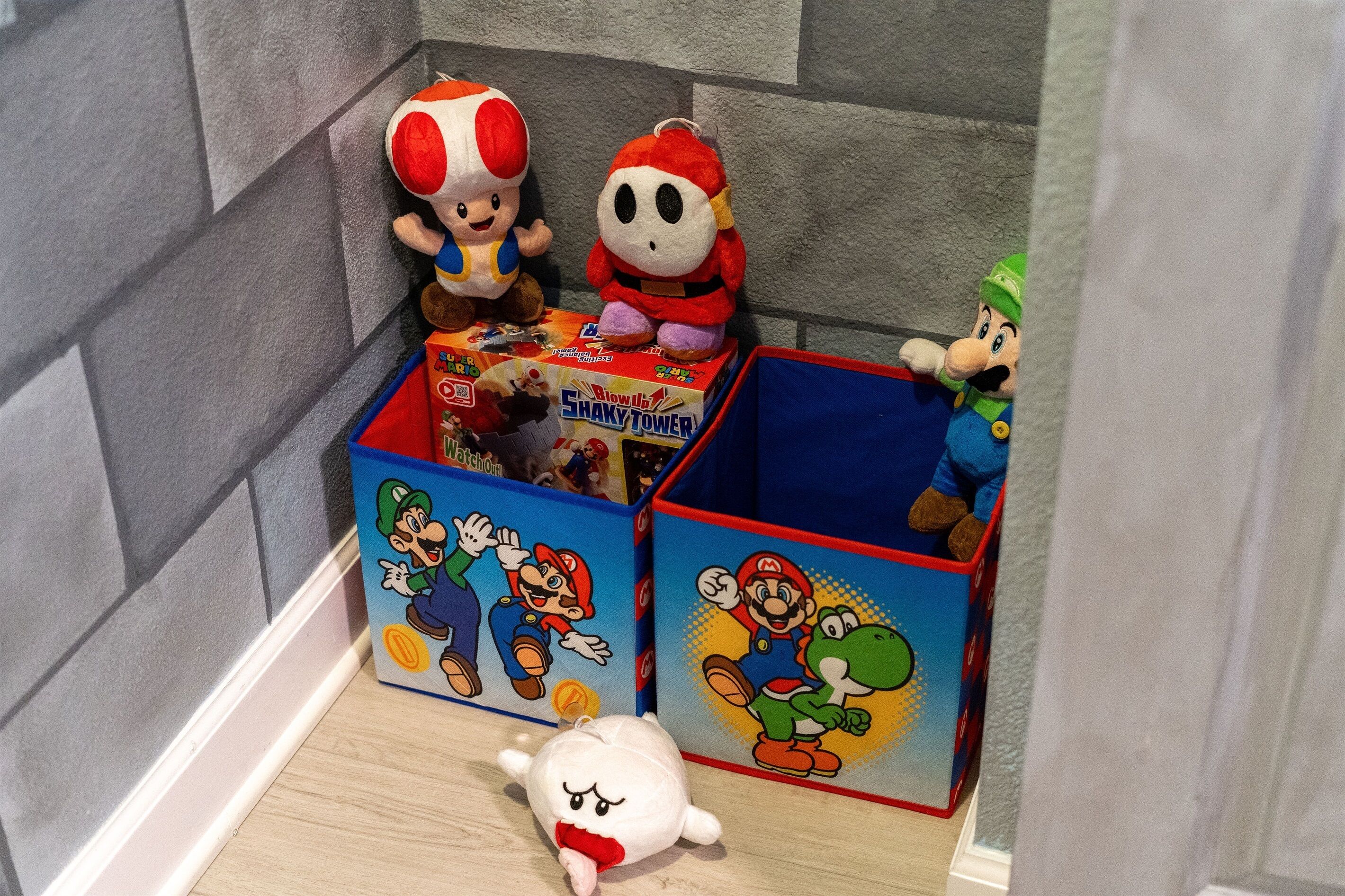 A corner with plush toys and a Shaky Tower toy box.