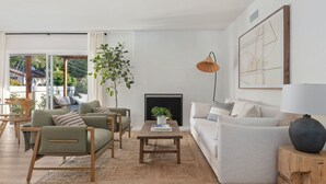 A modern living room with a sofa, chairs, a coffee table, and a fireplace.