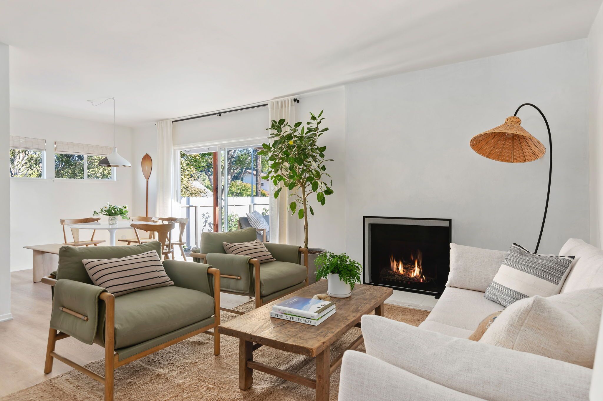 A modern living room with a fireplace, two sofas, a coffee table, and a dining area with a table and chairs.