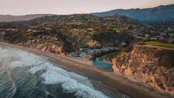 A coastal town with a beach, a river, and hills in the background.