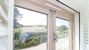 A window with a view of a rural landscape, including fields and trees. - Garstons Barn (Newport)