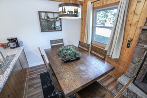 A wooden dining table with chairs, a coffee maker, and a decorative pine cone centerpiece. - Lazy R Cottages: 7a 2 Bedroom Cabin (Estes Park)