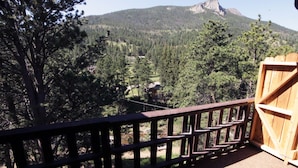 A wooden deck with a view of a forested mountain area. - Fawn Valley Inn: 293 1 Bedroom Condo (Estes Park)
