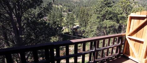 A wooden deck with a view of a forested mountain area.