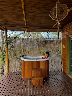 Une terrasse en bois avec un jacuzzi, une clôture en bambou et une porte verte.