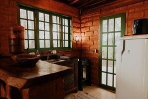 A rustic kitchen with a wooden counter, a stove, and a refrigerator. - Bangalô Ametista (Alto Paraíso de Goiás)