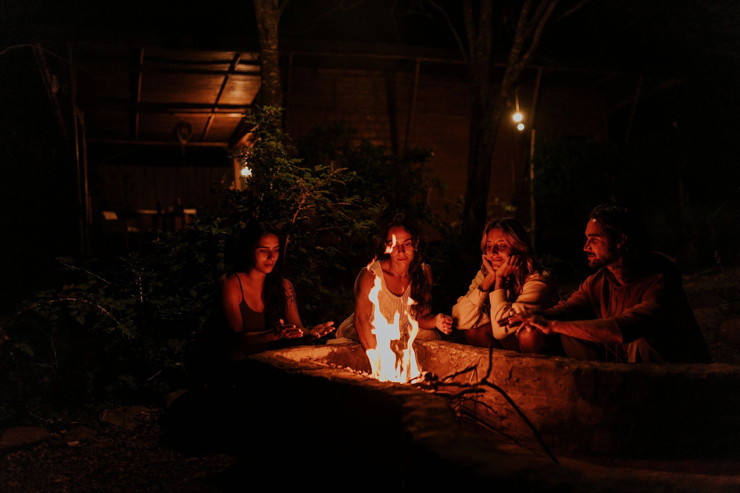 Um grupo de pessoas reunido em volta de uma fogueira à noite.