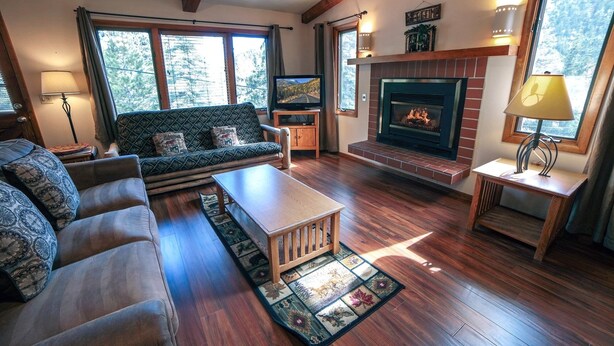 A cozy living room with a fireplace, a sofa, a coffee table, and a rug.