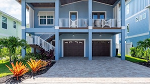A two-story house with a balcony, a garage, and a well-maintained garden. - 134 Pearl St 3 Bedroom Home by RedAwning (Fort Myers Beach)
