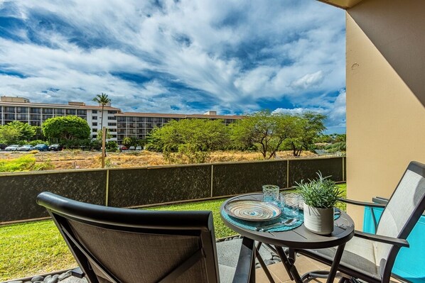 A balcony with a table, chairs, and a potted plant. - Pacific Shores B113 2 Bedroom Condo (Kihei)