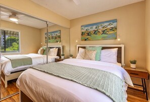 A bedroom with two beds, a large mirror, and artwork on the wall. - Pacific Shores B113 2 Bedroom Condo (Kihei)