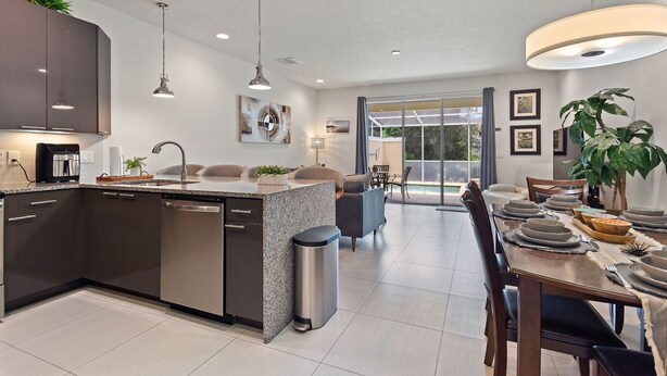 A modern kitchen with a central island, dark cabinetry, and stainless steel appliances. - Priceless Peace At Serenity By Shine Villas. 081 3 Bedroom Townhouse (Clermont)