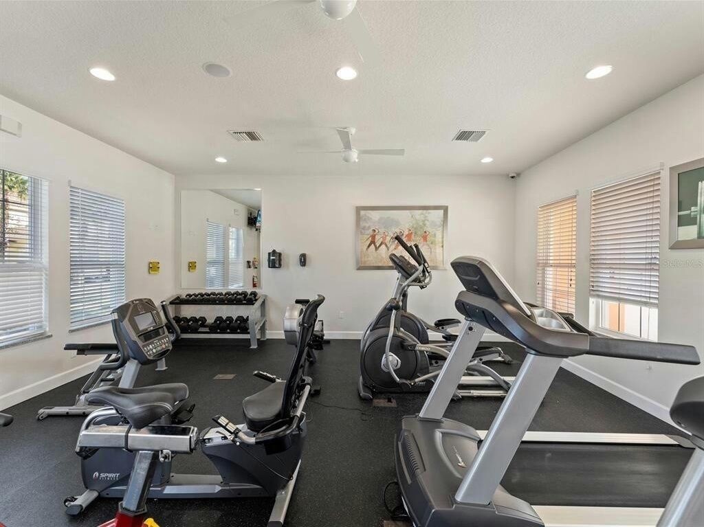 A gym with treadmills, elliptical machines, and dumbbells.