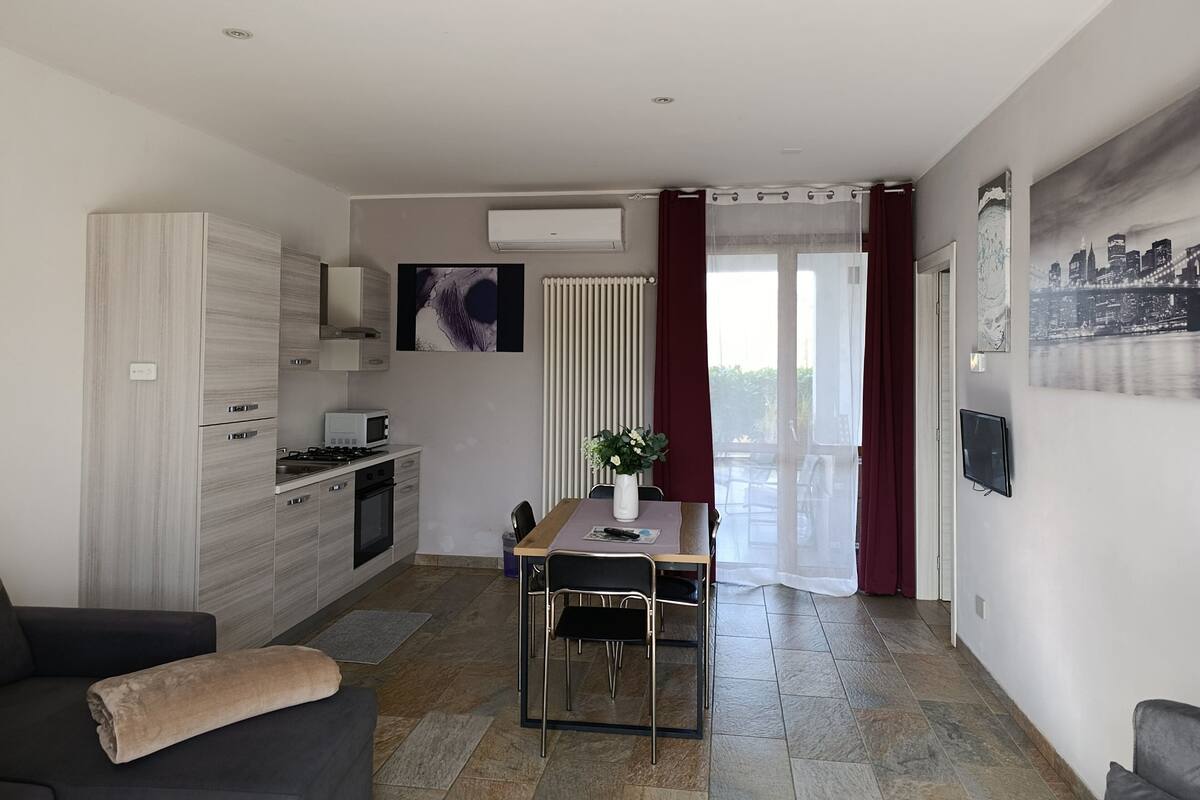 A modern kitchen with a microwave, stove, and cabinets, a dining area with a table and chairs, and a living room with a sofa.