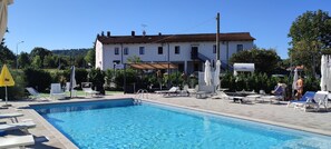 Una piscina al aire libre de temporada, sombrillas