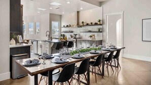 A modern kitchen with a central island, built-in appliances, and a dining area set for six. - Mollie's Landing 7 Bedroom Home (Hurricane)