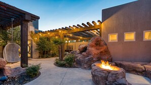 A patio area with a fire pit, rock formations, and a pergola with string lights. - Mollie's Landing 7 Bedroom Home (Hurricane)