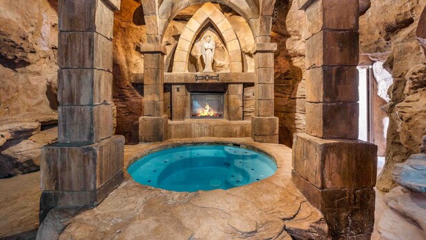 A stone-walled room with a central pool, stone pillars, and a fireplace. - Mollie's Landing 7 Bedroom Home (Hurricane)