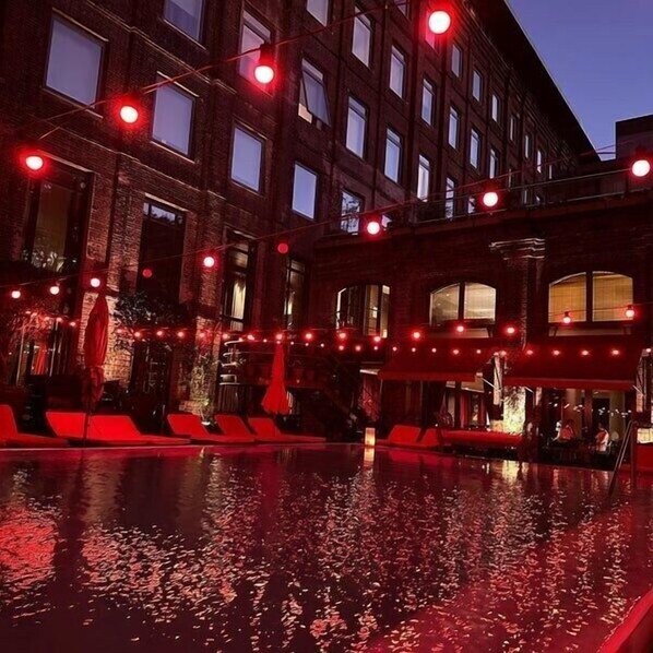 Un área de piscina con iluminación roja y sillones de descanso.