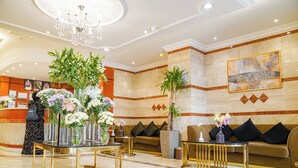 Un vestíbulo con mostrador de recepción, sofás y jarrones decorativos con flores.