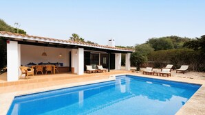Una piscina con sillas de descanso y un patio.