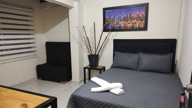 Une chambre à coucher avec un lit, une chaise, une petite table et un tableau accroché au mur.
