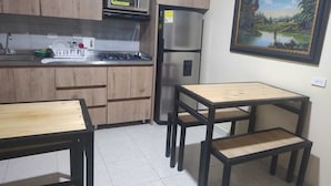 Une cuisine compacte dotée de meubles en bois, d’un four à micro-ondes, d’un réfrigérateur et d’un coin repas avec une table et des bancs.