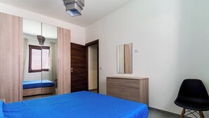 Une chambre à coucher avec un lit, une armoire, un miroir et une chaise.